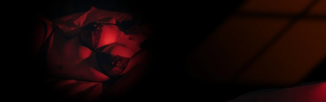 Evolova female sex robot in black lingerie under red ambient lighting.